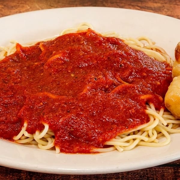 Spaghetti with red marinara sauce and two golden-brown garlic knots on a white plate.